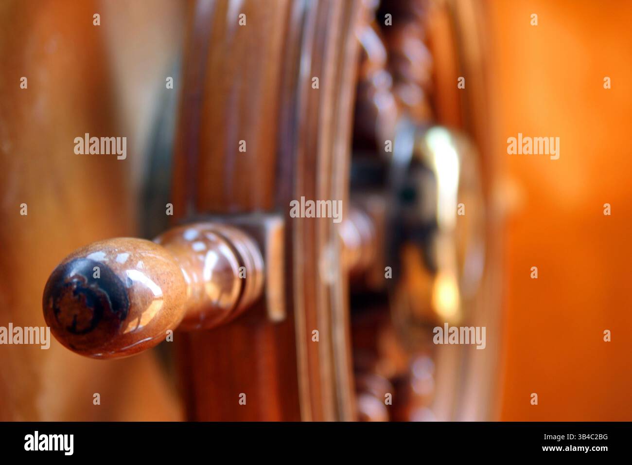 Primo piano di una maniglia del volante in legno con sfondo nautico caldo Foto Stock