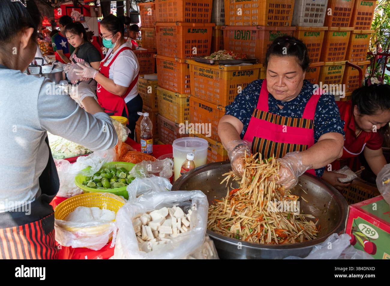 Un venditore di frutta che prepara una grande ciotola di insalata mista per i suoi clienti abituali e cerimonia di consegna delle elemosine buddiste in una delle bancarelle di frutta con un'ampia volontà Foto Stock