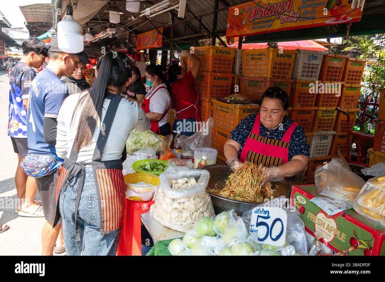 Un venditore di frutta che prepara una grande ciotola di insalata mista per i suoi clienti abituali e cerimonia di consegna delle elemosine buddiste in una delle bancarelle di frutta con un'ampia volontà Foto Stock