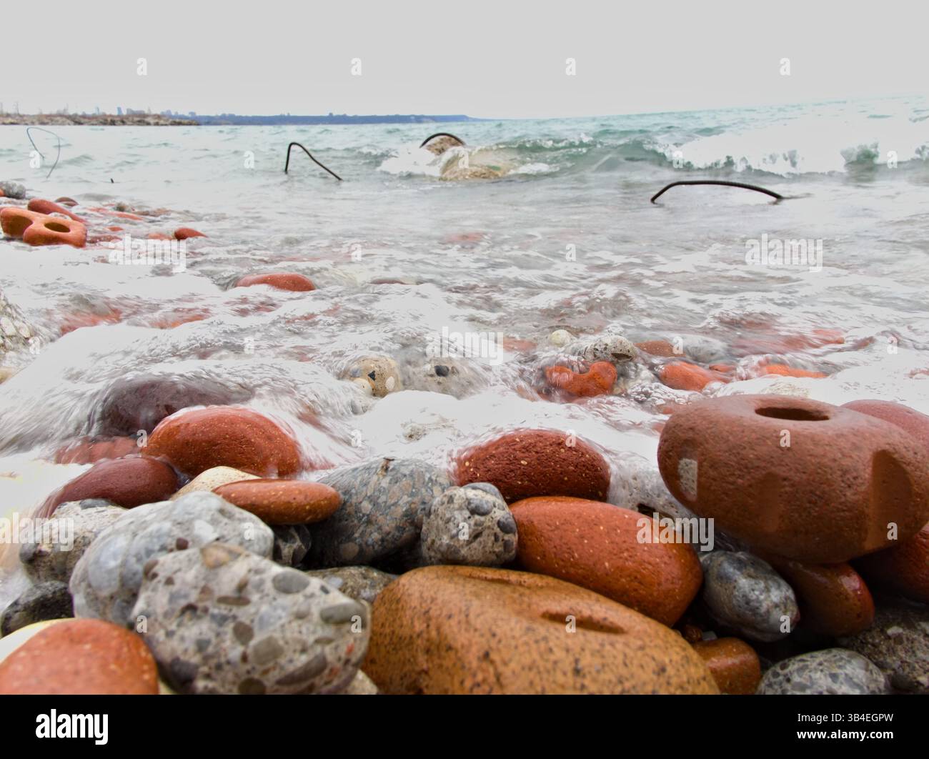 Il bordo della spiaggia dell'Ontario, fatto di detriti di pietra artificiale, è tornato alla natura. Il lago lucida ogni bordo in qualcosa di bello. Foto Stock