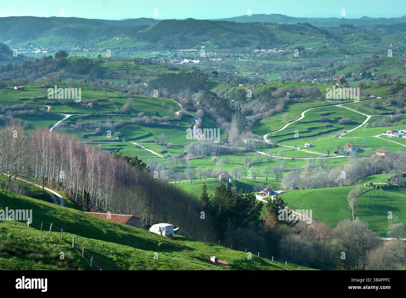Vista aerea mozzafiato della vibrante valle verde con strade tortuose, terreni agricoli e foreste sotto il cielo azzurro. Esles, santa maria de cayon, cantabr Foto Stock