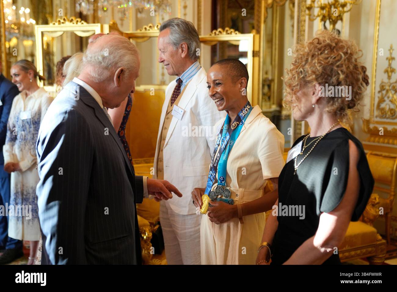 Britain's King Charles III speaks with broadcaster and presenter Adele Roberts, wearing her medals from the TCS London Marathon and Abbott World Marathon Majors, during a reception in Buckingham Palace, London, in celebration of community-based initiatives raising awareness about cancer and supporting those living with cancer, Wednesday April 30, 2025. (Andrew Matthews/Pool Photo via AP) Foto Stock
