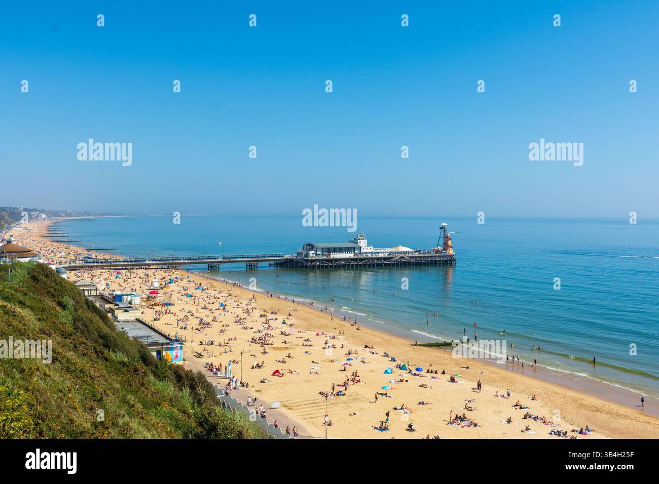 West Cliff Beach, Bournemouth, Regno Unito - 30 aprile 2025: Vista sulla scogliera dei bagnanti sulla spiaggia e del molo di Bournemouth. Foto Stock
