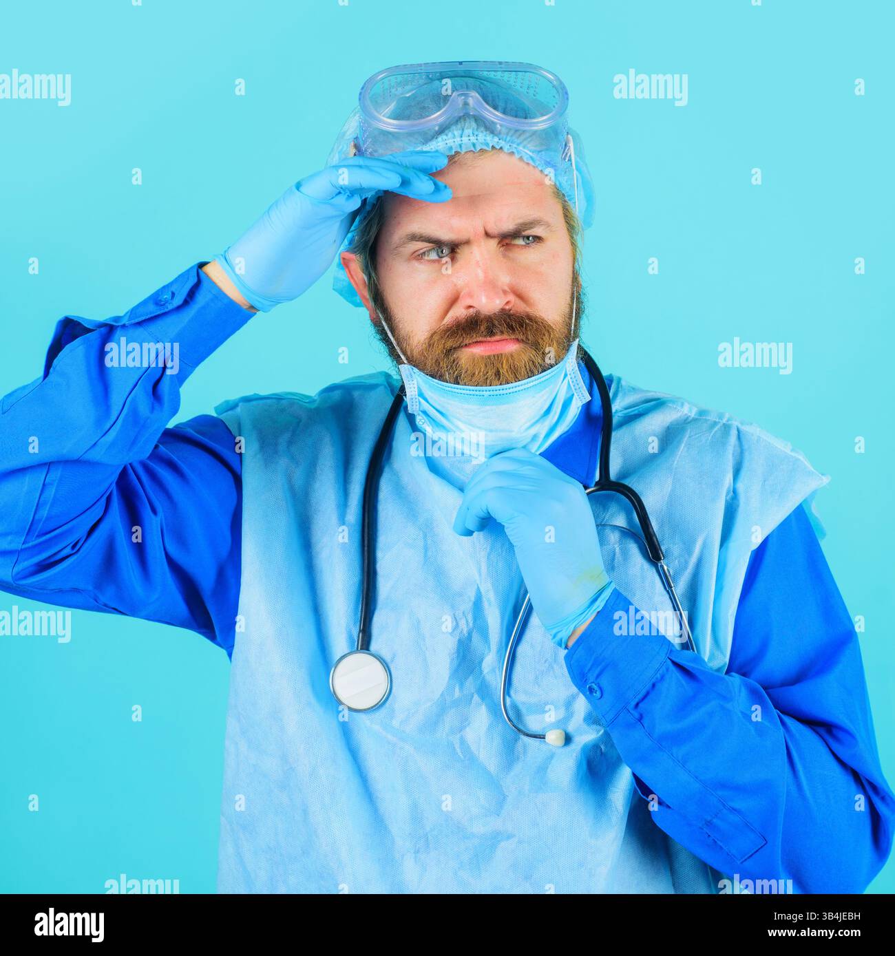 Medico serio in tuta protettiva, maschera medica e occhiali di sicurezza con stetoscopio, ritratto. Medico uomo in uniforme medica e guanti di gomma con Foto Stock