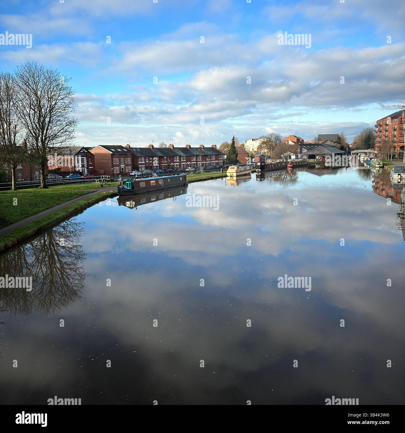 Scena del canale di Chester con riflessi di soffici nuvole in acque calme, barca sul canale e fila di case in una giornata di sole brillante in primavera. - Immagine stock catturata con smartphone
