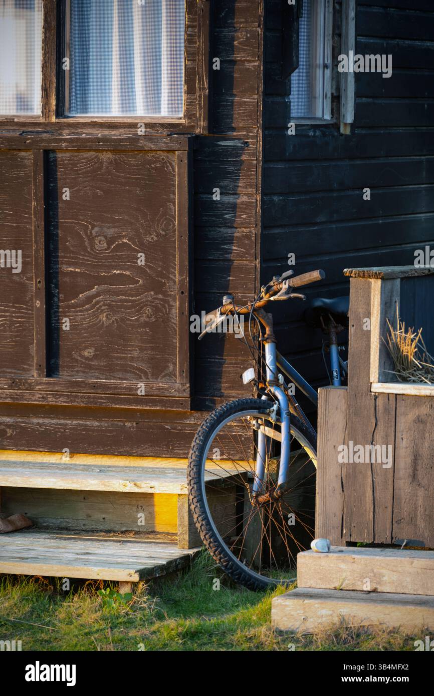 bicicletta solitaria parcheggiata tra rifugi in spiaggia, walberswick, suffolk, inghilterra Foto Stock