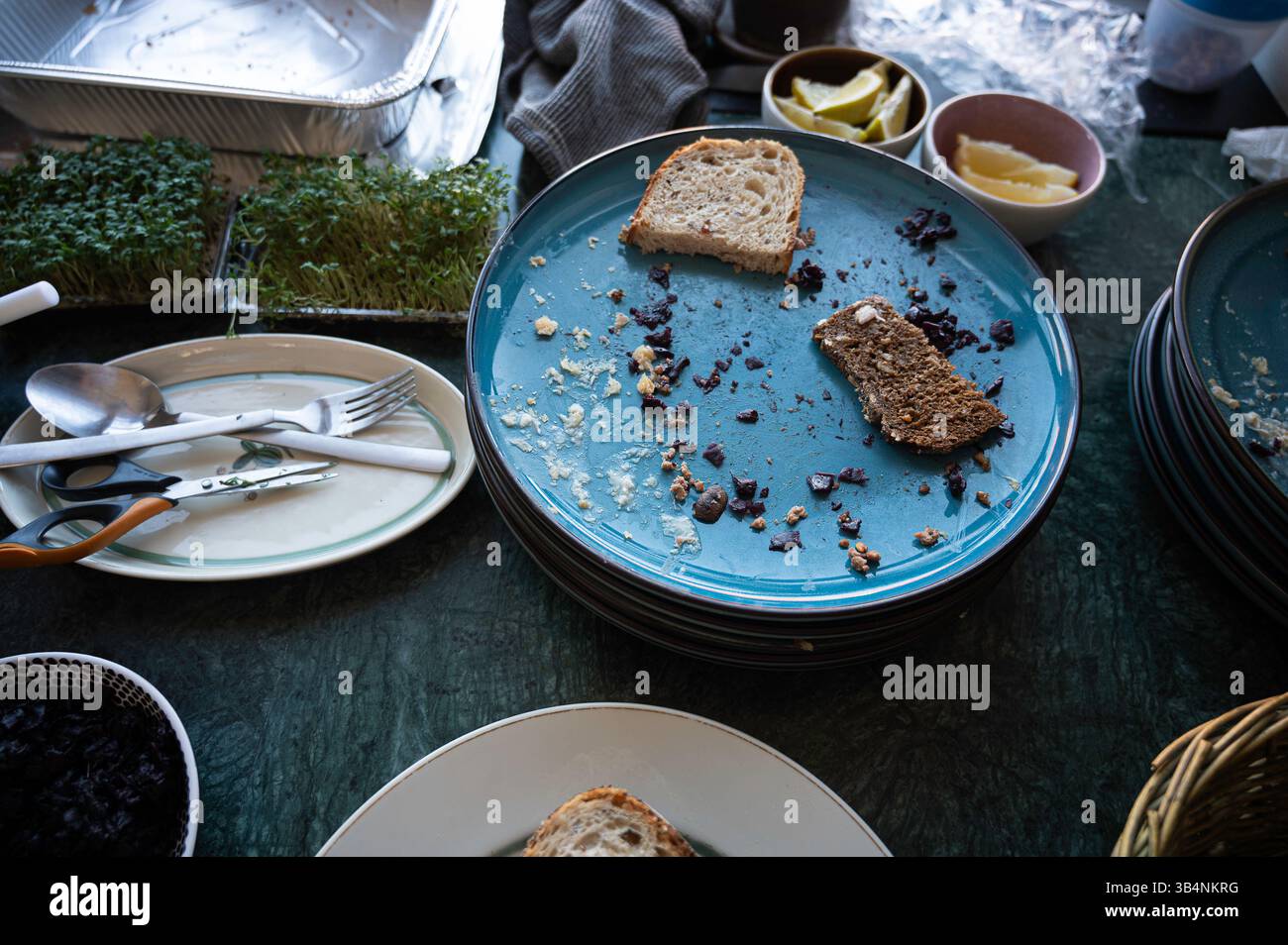 Piatti con fette di pane e avanzi sui piatti dopo un pasto, Danimarca, 24 aprile 2025 Foto Stock