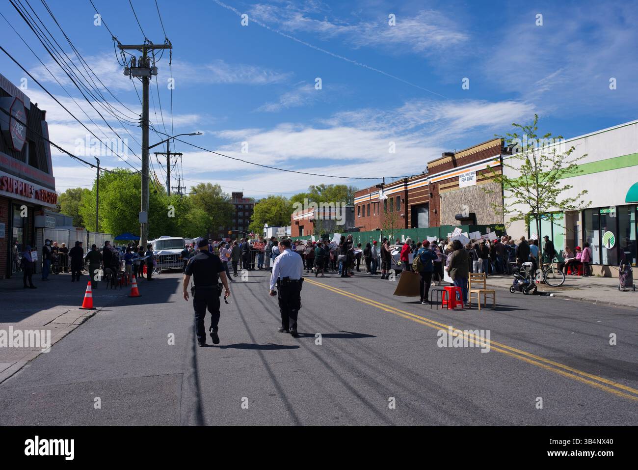 Dimostrazione di strada con un grande gruppo di persone che hanno dei cartelli, osservati dagli agenti di polizia. La scena è ambientata su una strada della città con edifici e pow Foto Stock