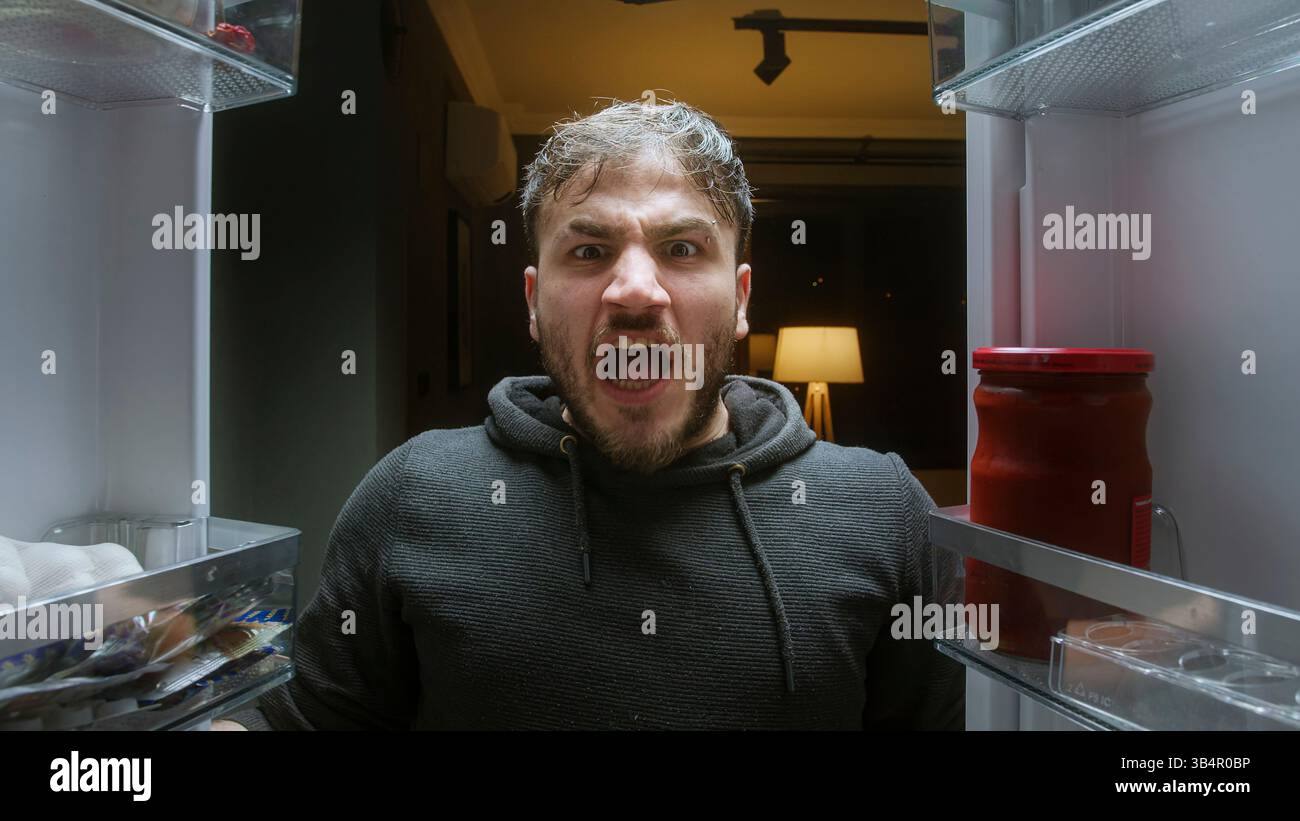 Uomo arrabbiato urlando con le mani vuote all'interno del frigorifero dal punto di vista del frigorifero Foto Stock