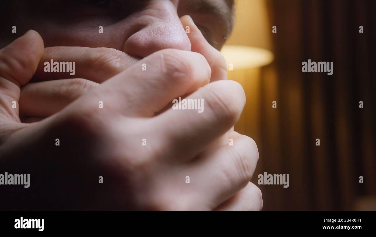 Giovane in difficoltà che copre il viso con le mani, affrontando il dolore emotivo e la pressione sociale Foto Stock