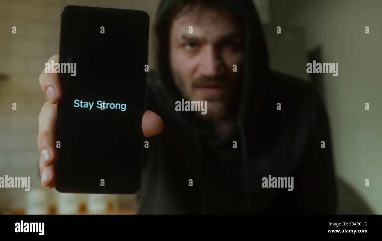 Uomo che tiene in mano uno smartphone che mostra il messaggio Stay strong motivazione e concetto di supporto Foto Stock