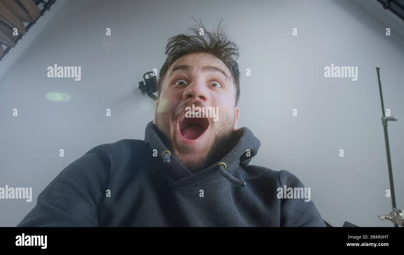 Uomo eccitato che reagisce con stupore mentre sboccia un pacchetto da una prospettiva a basso angolo Foto Stock