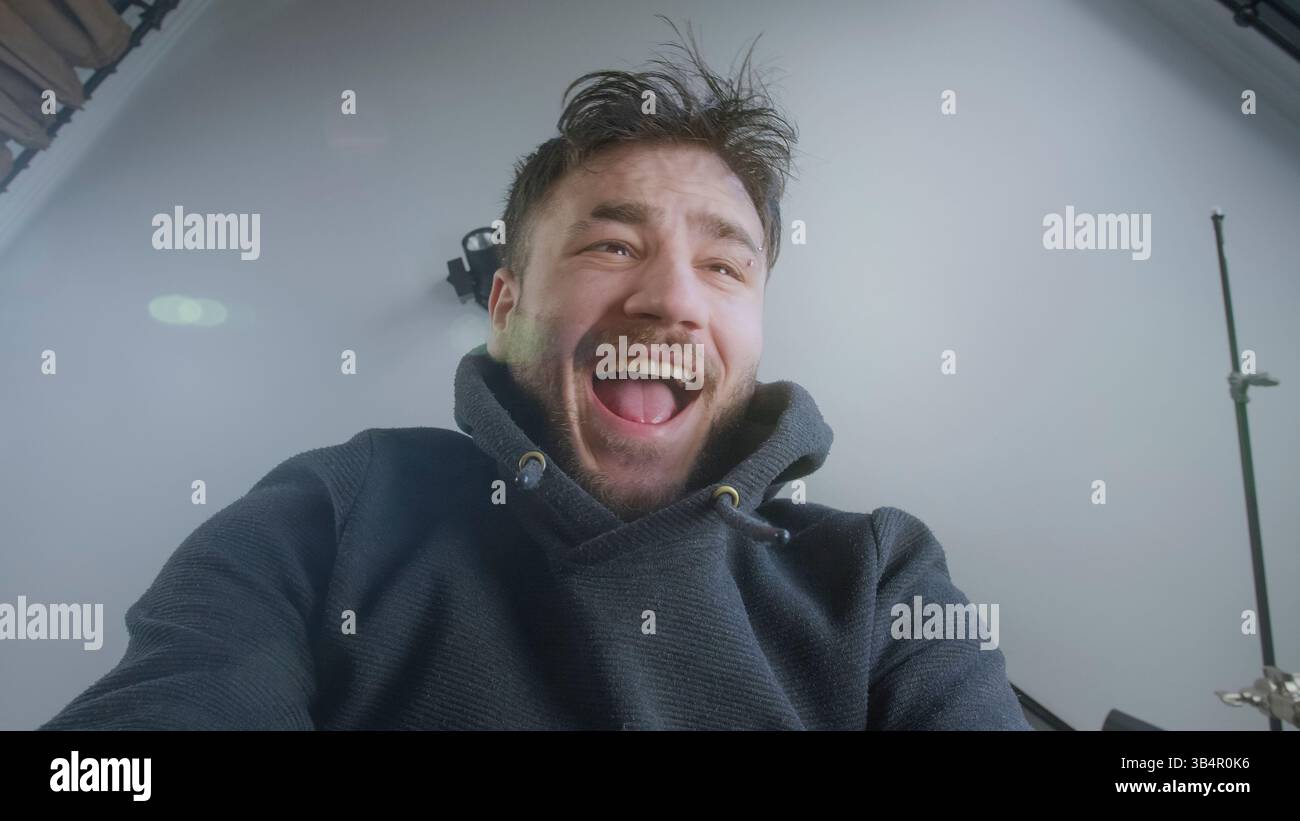 Young Man reagisce con stupore mentre sboccia un pacchetto da una prospettiva a basso angolo Foto Stock
