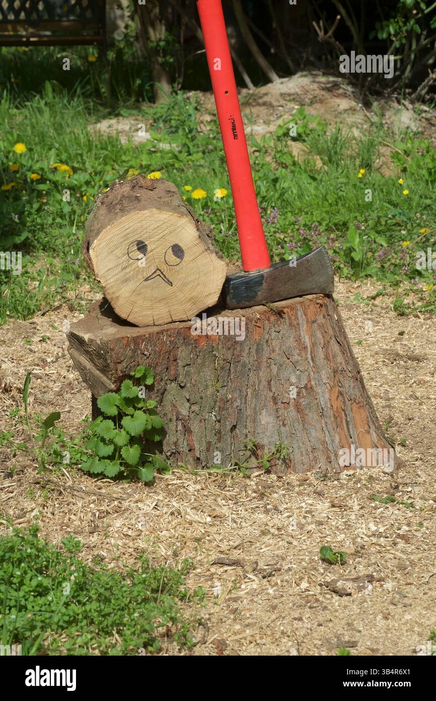 troncare l'albero intorno al blocco di triturazione accanto al maul che si divide con la faccia preoccupata disegnata con la penna Foto Stock