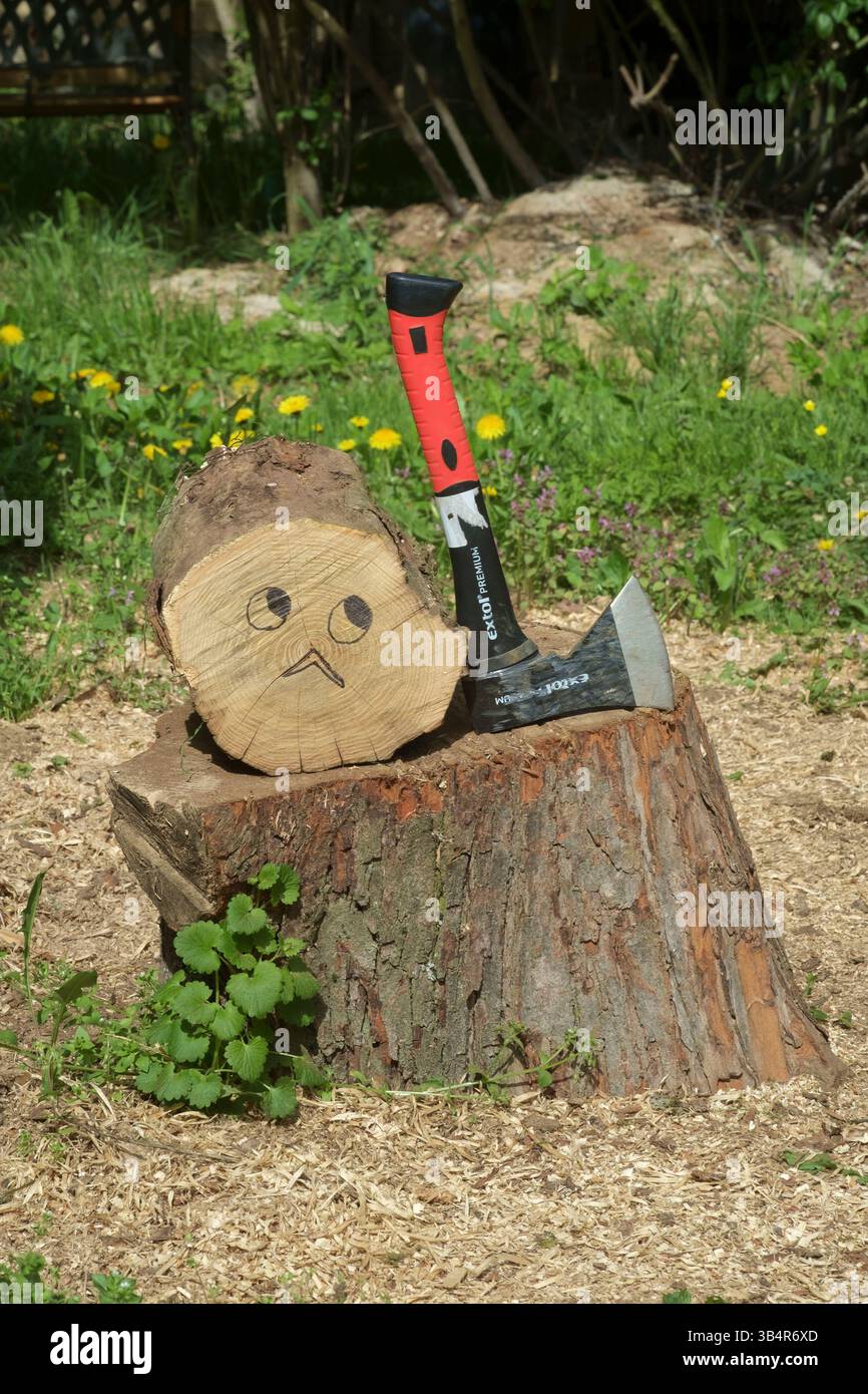 troncare l'albero sul blocco di triturazione accanto all'ascia con la faccia preoccupata disegnata con la penna Foto Stock