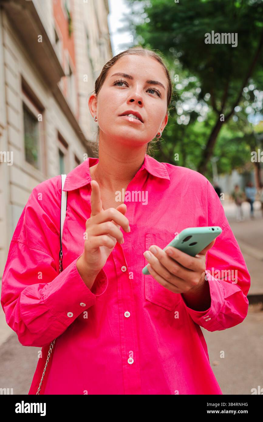 Verticale. Una ragazza pensiva profondamente impegnata nel pensiero mentre utilizza il suo telefono cellulare, mostrando un momento di contemplazione, curiosità e connessione Foto Stock