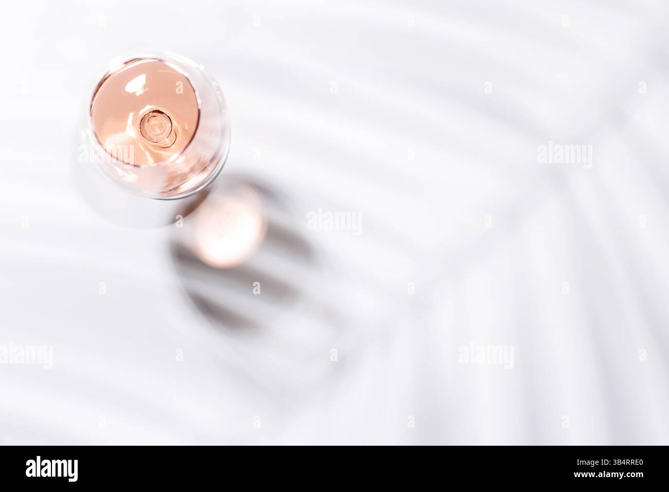 Un bicchiere di vino rosa riempito con la bevanda rosa-blush, posto su uno sfondo luminoso ed elegante. Perfetto per feste o momenti di relax Foto Stock