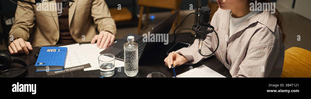 Donna che discute Book with Man durante il podcast Foto Stock