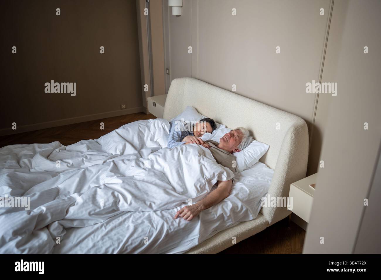 Marito e moglie maturi e tranquilli dormono sonni tranquilli mentre si abbracciano insieme in un'accogliente camera da letto Foto Stock