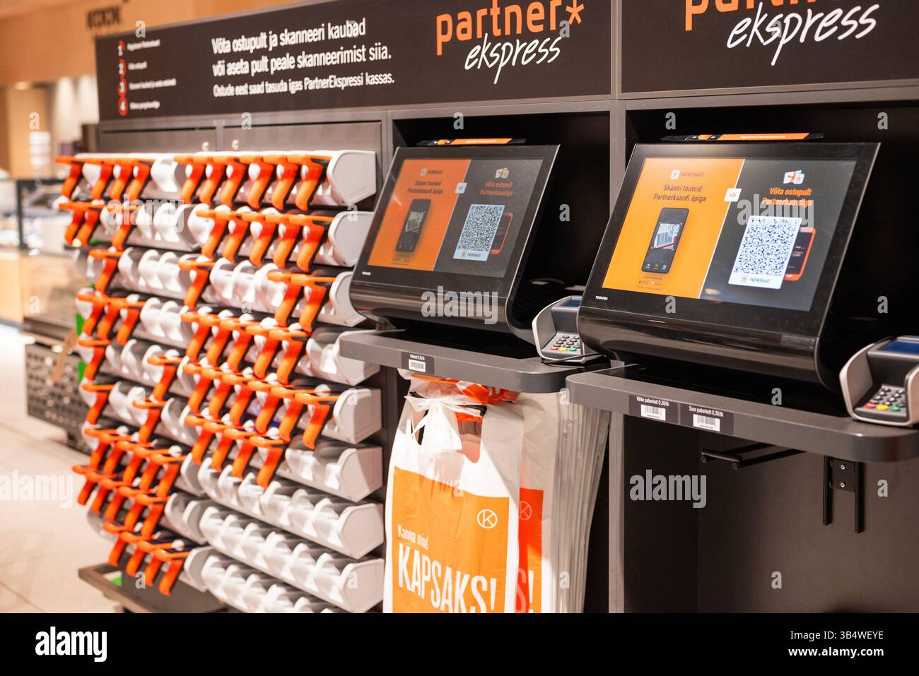 28 aprile 2025, Tallinn, Estonia Un acquirente utilizza uno scanner di codici a barre portatile per eseguire la scansione dei prodotti in un supermercato moderno. L'immagine illustra l'auto-servitù Foto Stock