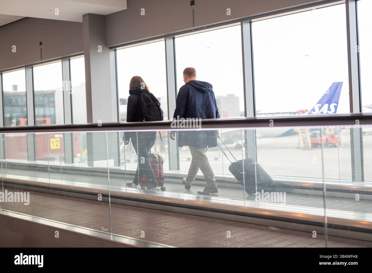 27 aprile 2025 Stoccolma Svezia , passaggio corridoio tra i terminal dell'aeroporto di Arlanda con scala mobile e passeggeri Foto Stock