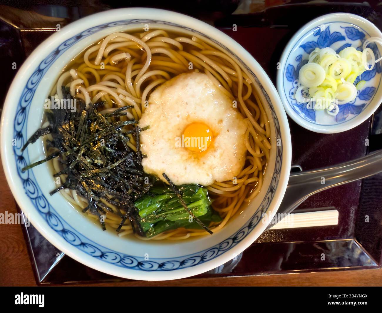 Vista dall'alto della zuppa di noodle udon con uovo di quaglia, alghe marine e spinaci Foto Stock
