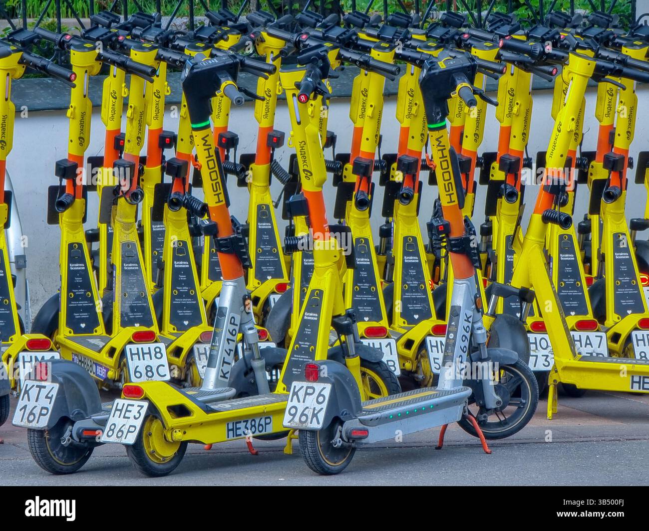 Primo piano di molti e-scooter gialli luminosi parcheggiati sul marciapiede / marciapiede; Whoosh Foto Stock