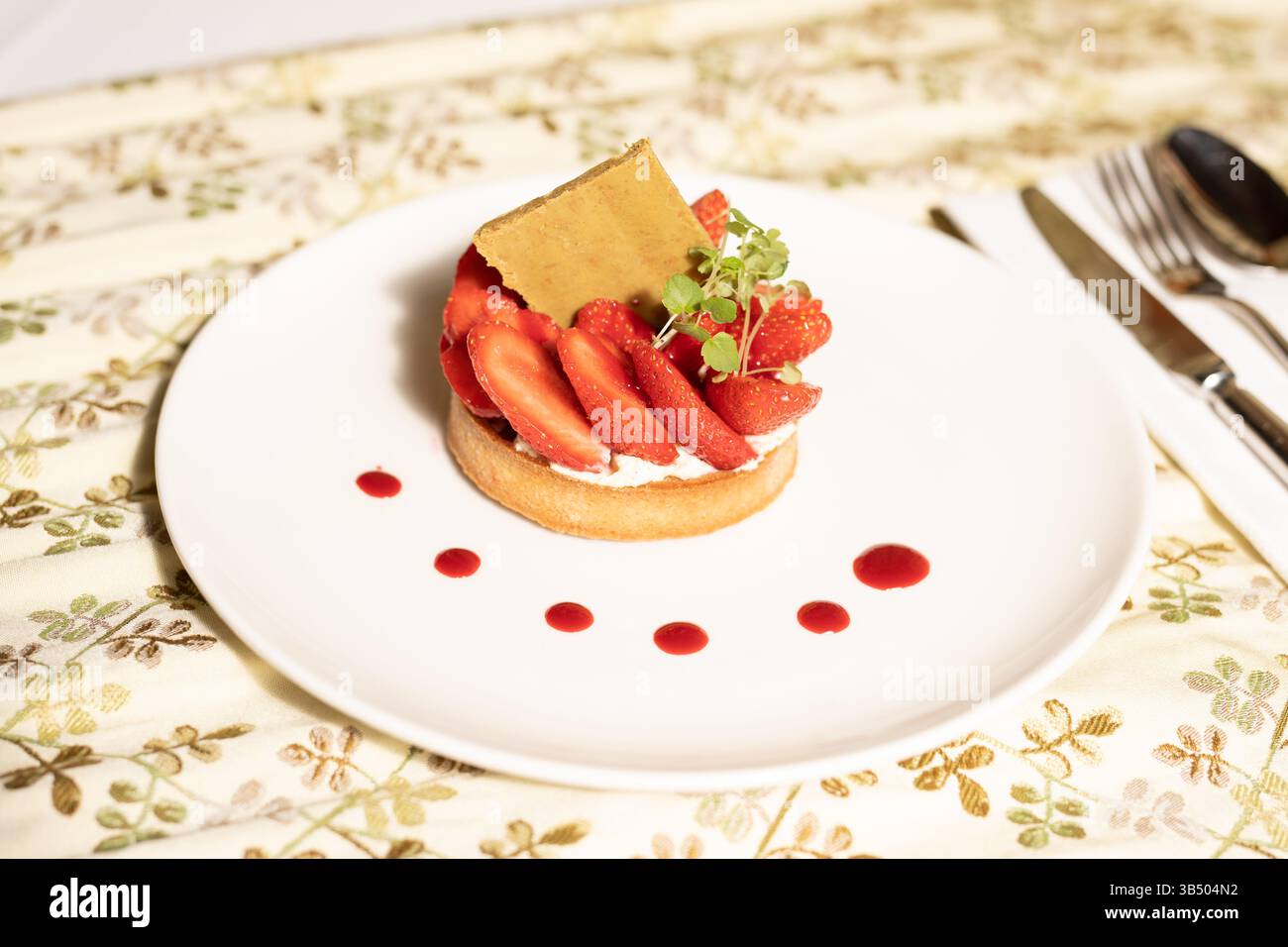 Crostata di fragole su una placcatura elegante: Dessert gourmet con pasta croccante e salsa rossa Foto Stock