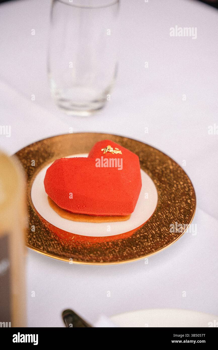 Romantico dessert in velluto rosso: Pasticceria di lusso a forma di cuore e cena elegante Foto Stock