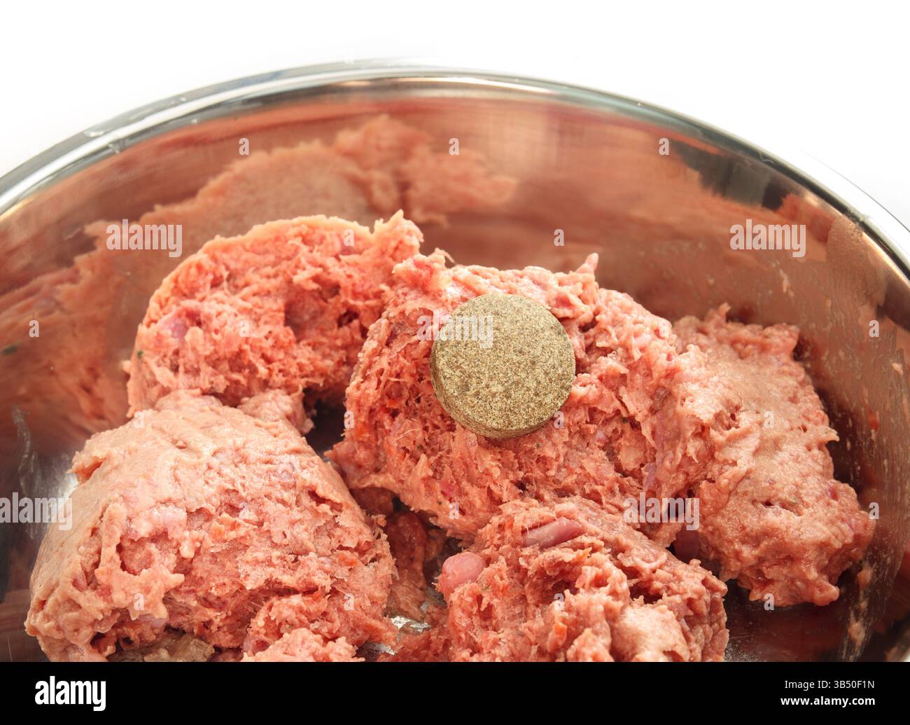 Cibo per cani con farmaci o integratori vitaminici. Recipiente in acciaio inox con cibo crudo per animali e una grande pillola. Nascondere la medicina nel cibo umido per animali domestici. Accesso per animali domestici Foto Stock