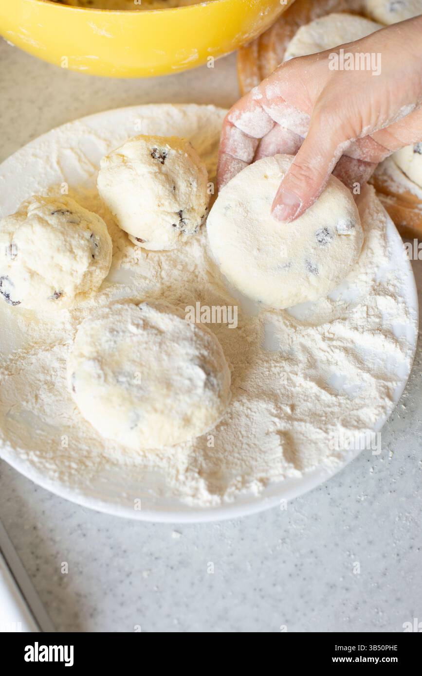 Le mani caucasiche preparano frittelle di formaggio fresco con uvetta Foto Stock