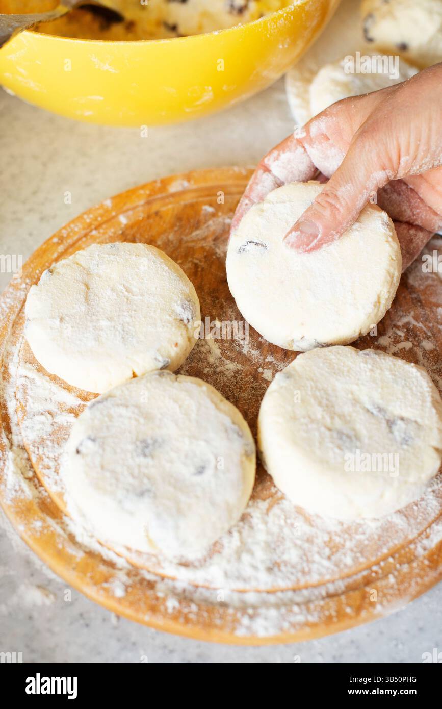 Le mani caucasiche preparano frittelle di formaggio fresco con uvetta Foto Stock