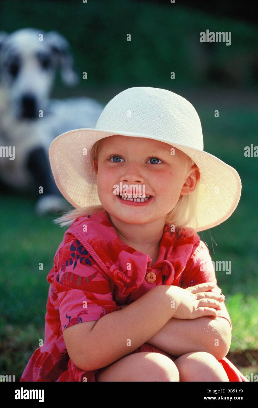 Bambina seduta in un giardino soleggiato. Foto Stock