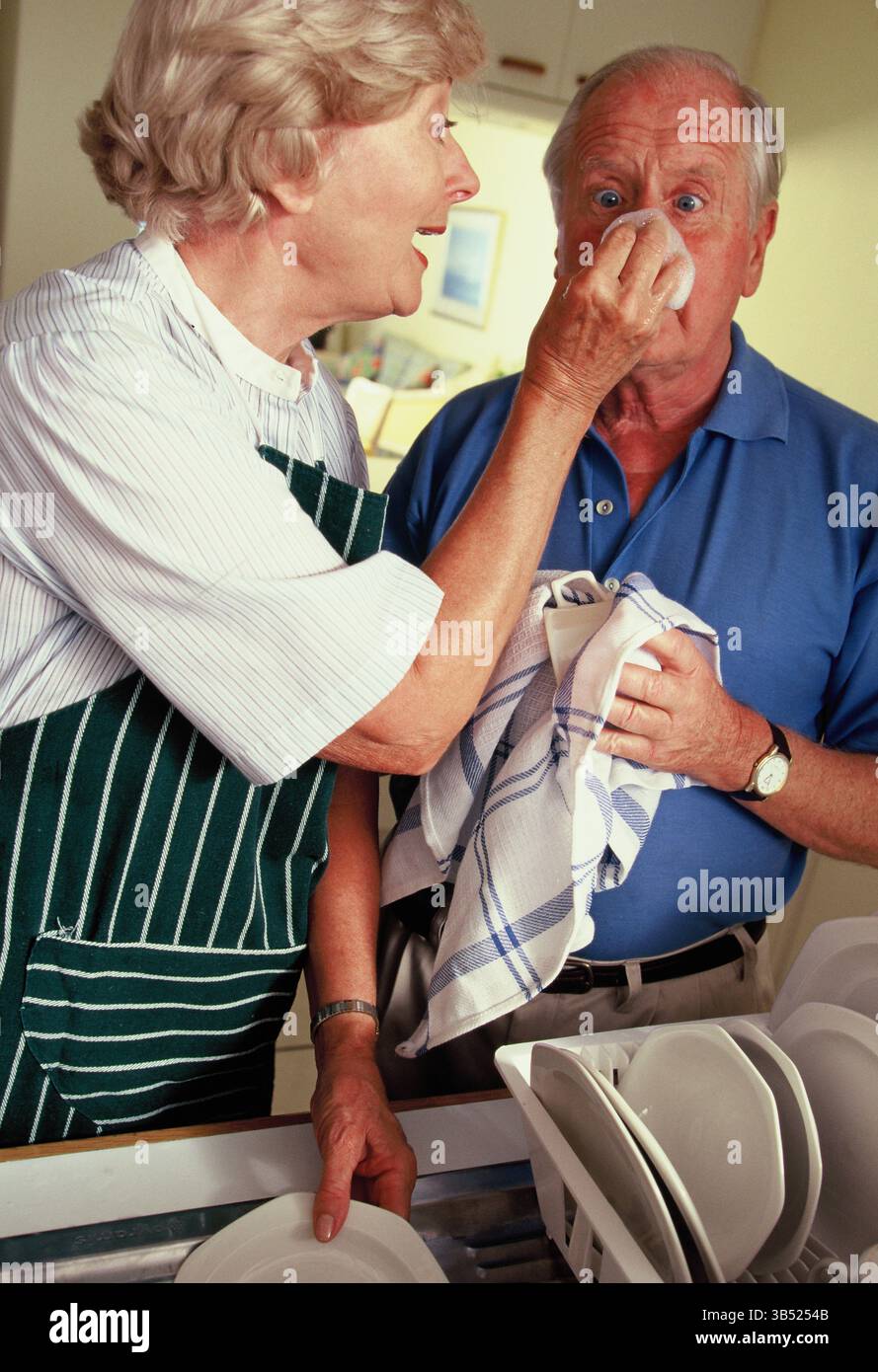 La coppia senior lava i piatti in cucina a casa. Foto Stock