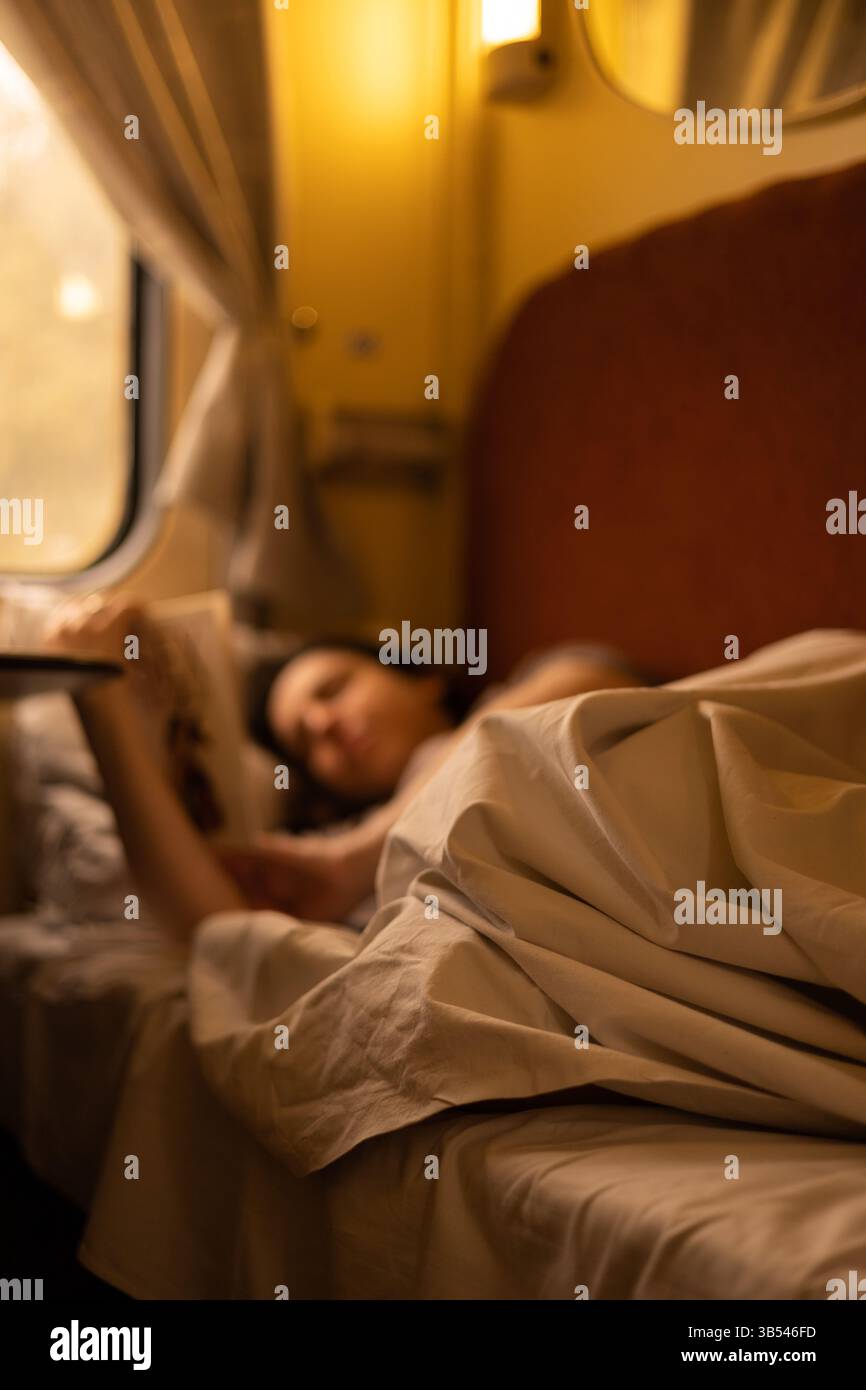 Donna che legge un libro a letto Foto Stock