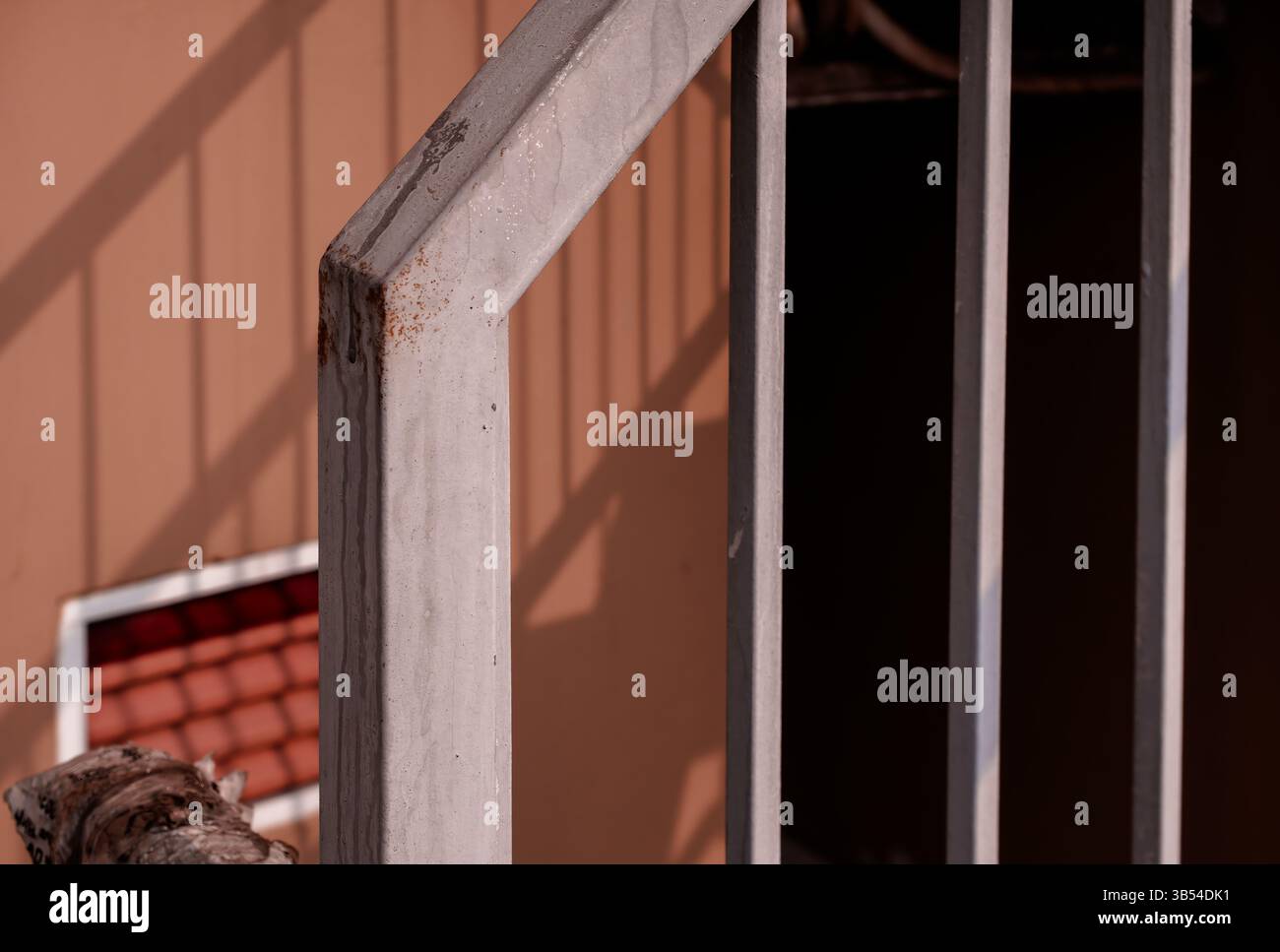 Rossiccio in metallo che getta ombre su una parete color pesca Foto Stock