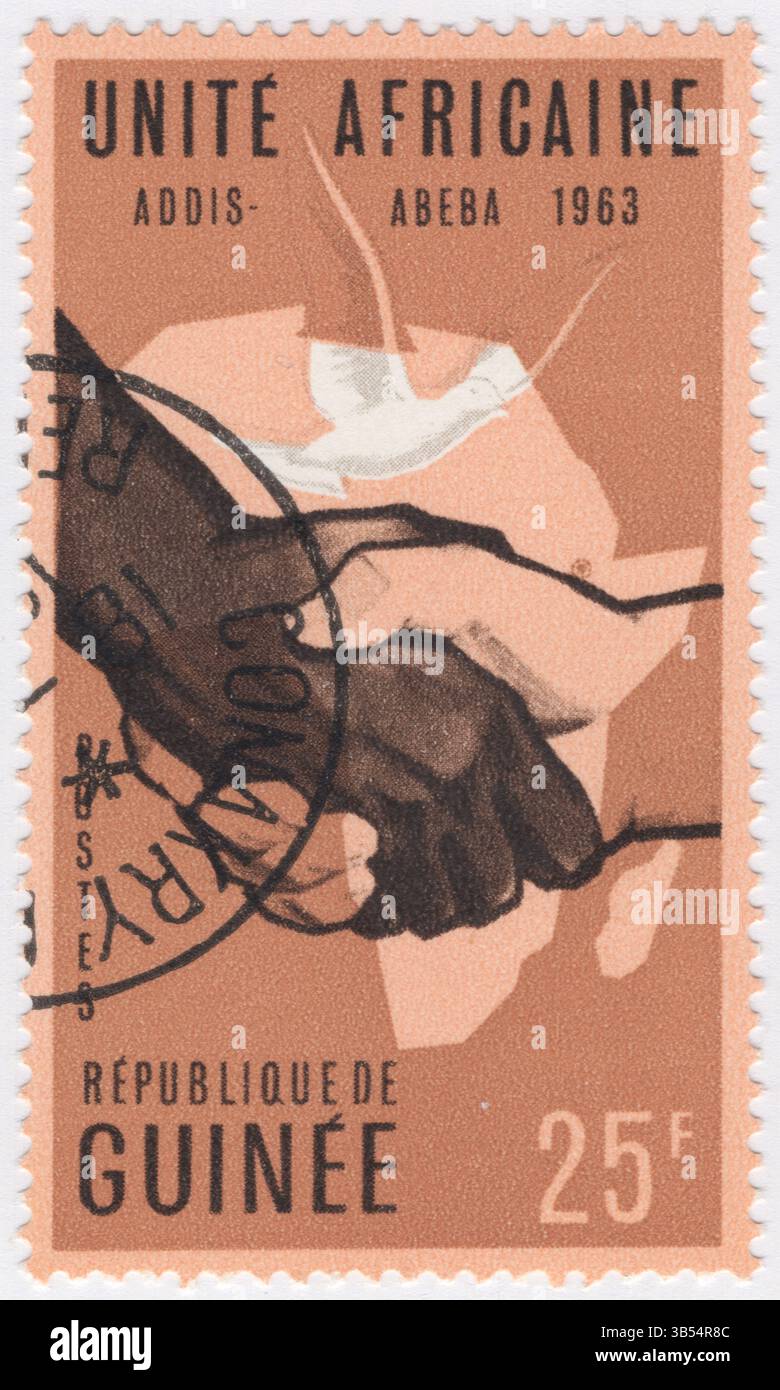 GUINEA - 1963 maggio 22: Francobollo da 25 franchi marrone bister e marrone scuro raffigurante una composizione allegorica con una stretta di mano, una mappa e una colomba. Conferenza dei capi di Stato africani per l'unità africana, Addis Abeba. L'Organizzazione (OAU) è stata un'organizzazione intergovernativa fondata il 25 maggio 1963 ad Addis Abeba, Etiopia, con 32 governi firmatari. Alcuni degli obiettivi chiave dell'OUA erano di incoraggiare l'integrazione politica ed economica tra gli stati membri e di sradicare il colonialismo e il neo-colonialismo dal continente africano Foto Stock