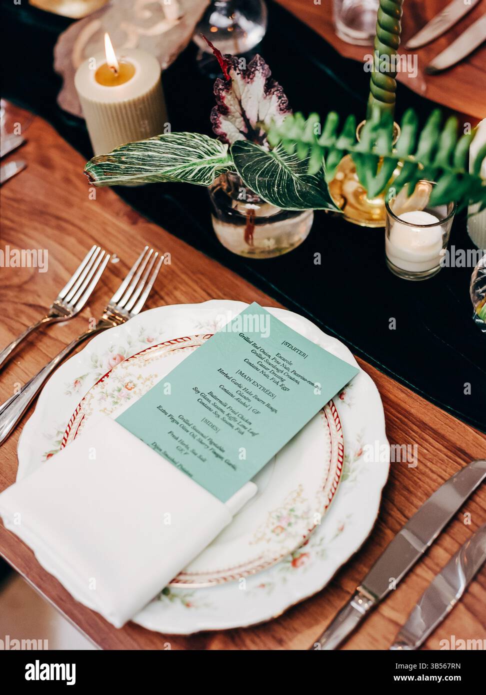 Un tavolo splendidamente allestito presenta raffinata porcellana, eleganti posate e un menu' accuratamente realizzato per un'occasione speciale. Foto Stock