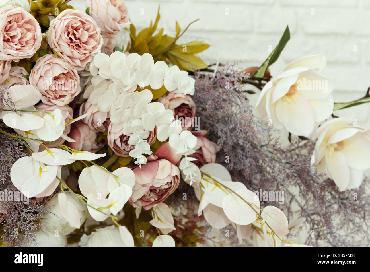 Bouquet di grazioso fiore ornamentale bianco in materiale e plastica appeso su una parete come parte dell'interno Foto Stock