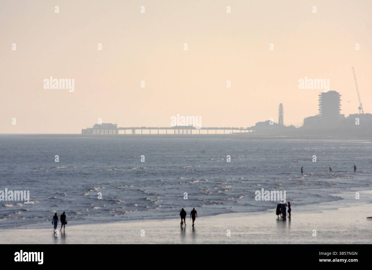 Gente che cammina sulla spiaggia di Shoreham, West Sussex, con il molo di Worthing in lontananza Foto Stock