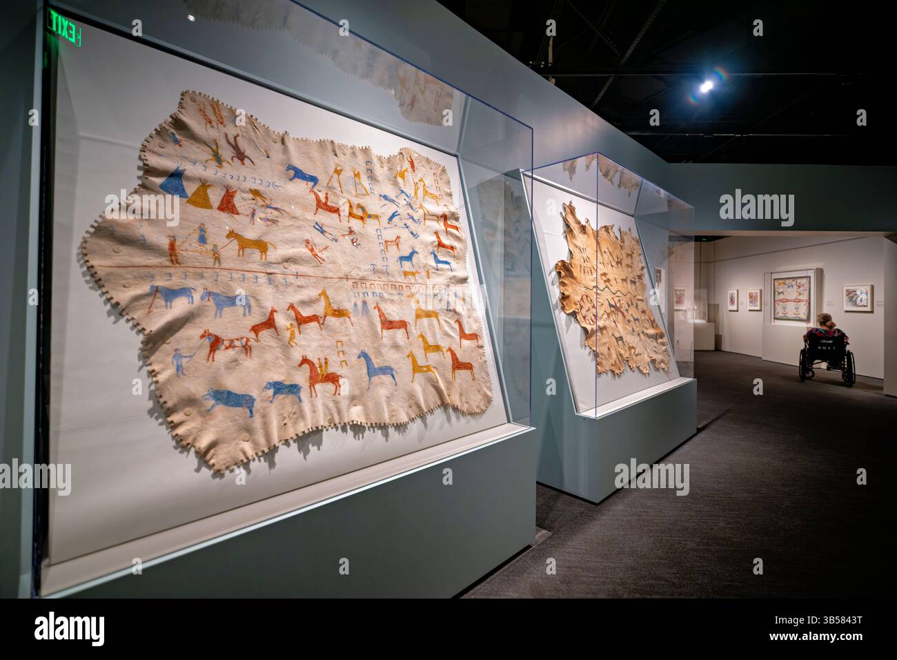 WASHINGTON DC — An Elkskin Robe (ca. 1920) attribuito a James White Calf (Blackfeet, ca. 1858-1970) esposto al National Museum of the American Indian. Il nascondiglio dipinto intricatamente registra gli onori di guerra di Mountain Chief, un importante leader dei piedi Neri noto per le battaglie contro Sioux, A'aninin, Cree e Assiniboine nemici. Ad accompagnare l'abito c'è una fotografia del 1916 di Harris & Ewing che mostra l'etnomusicologo Frances Densmore che registra il capo della montagna per il Bureau of American Ethnology. Foto Stock