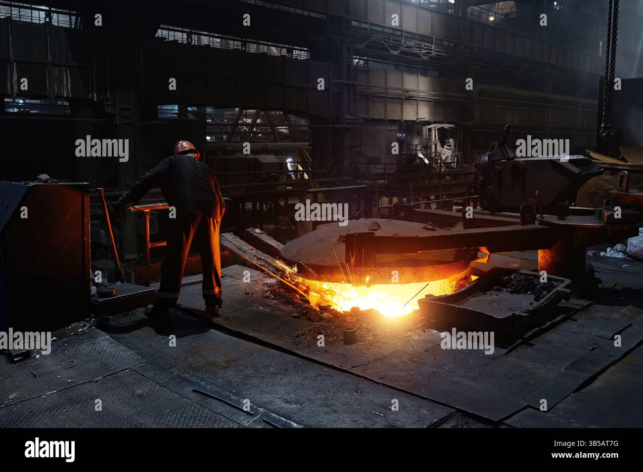 Metallurgici che prelevano campioni di metallo fuso liquido. Foto Stock