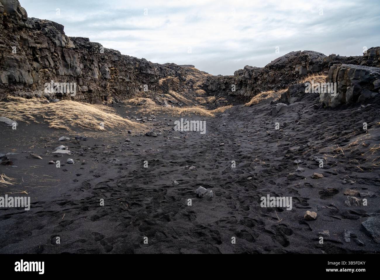 Terreno islandese fatto di rocce e sabbia nera vicino alla penisola di Reykjanes durante una giornata nuvolosa Foto Stock