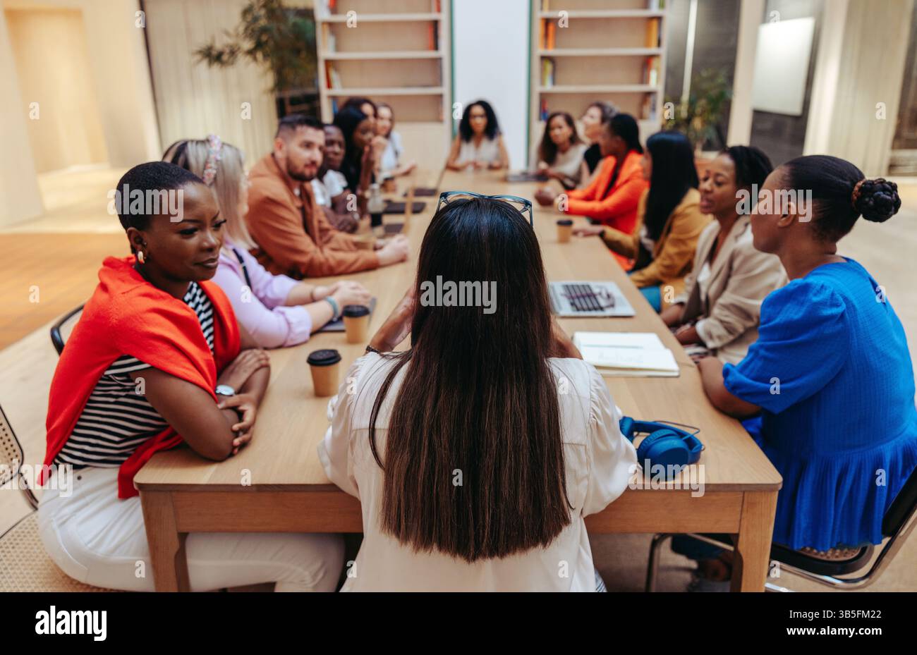 Un gruppo diversificato di professionisti si è riunito per un incontro in un'agenzia creativa. L'ambientazione offre un ambiente stimolante in cui i membri del team condividono le idee Foto Stock