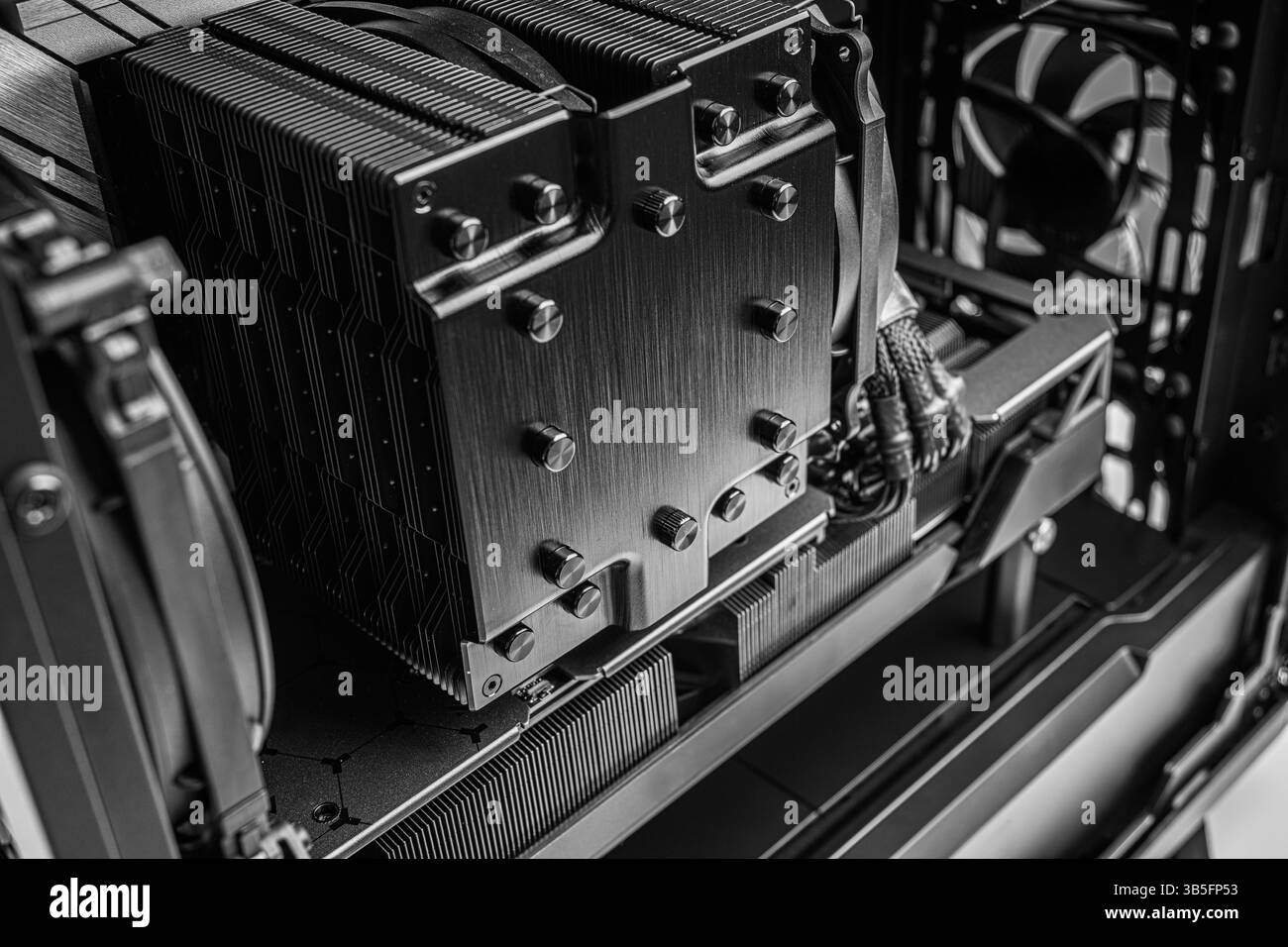 Uno scatto ravvicinato di un processore di raffreddamento della CPU, cavi di alimentazione intrecciati e alette di raffreddamento all'interno di un PC desktop personalizzato Foto Stock