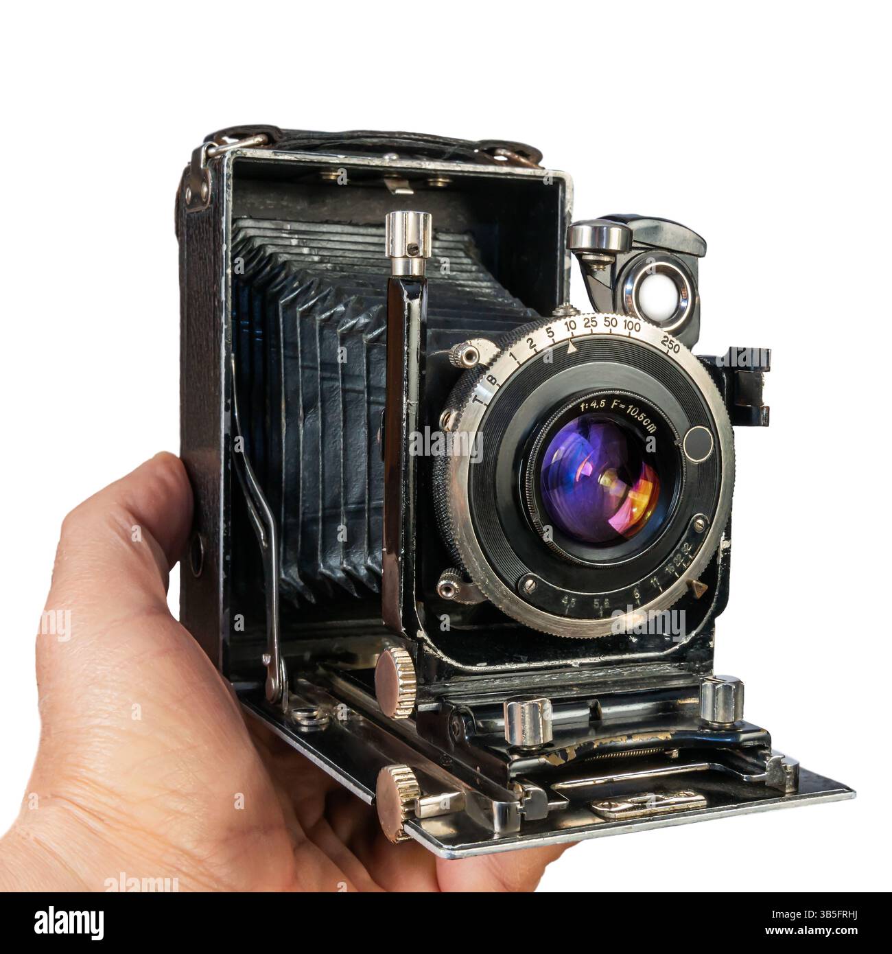 Una mano afferra una macchina fotografica d'epoca, mettendo in risalto la sua meccanica dettagliata e il design artistico tipico della prima metà del XX secolo. Isolato su Foto Stock