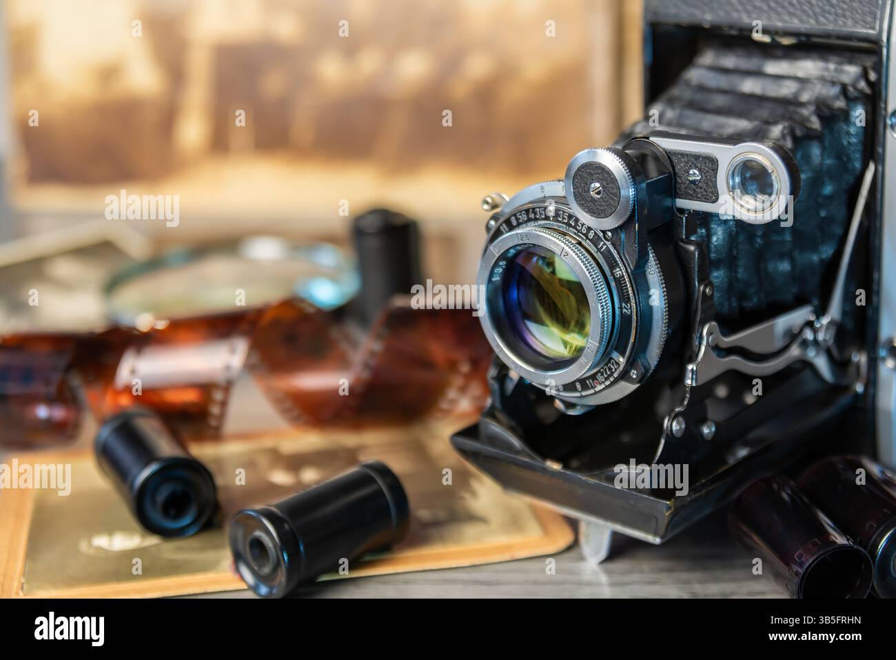 Una macchina fotografica d'epoca si trova su una superficie di legno circondata da vecchie fotografie, che evocano ricordi di momenti e storie passate. Foto Stock