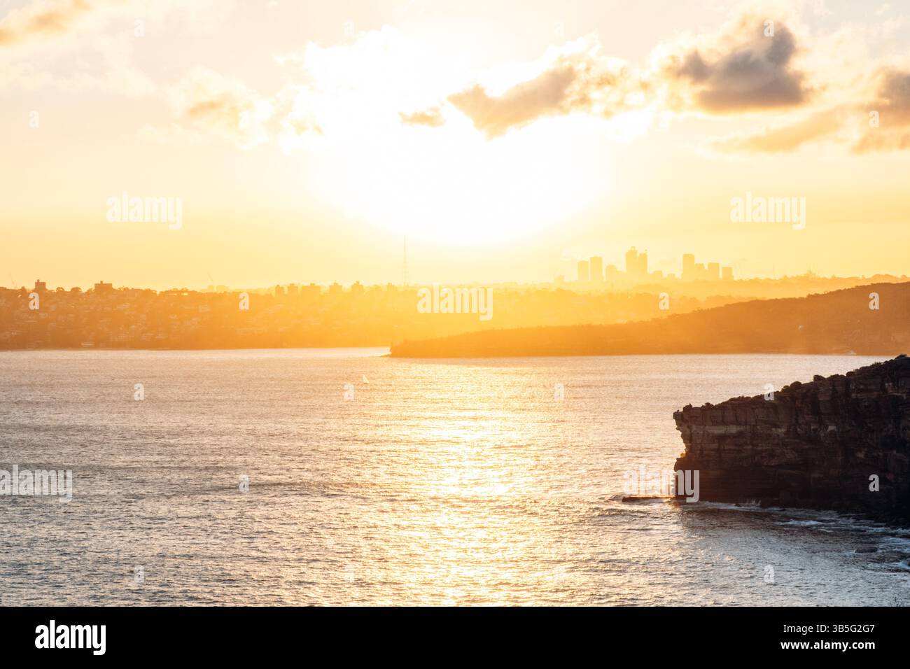 Vista del tramonto sulle scogliere oceaniche e sullo skyline di North Sydney in lontananza Foto Stock