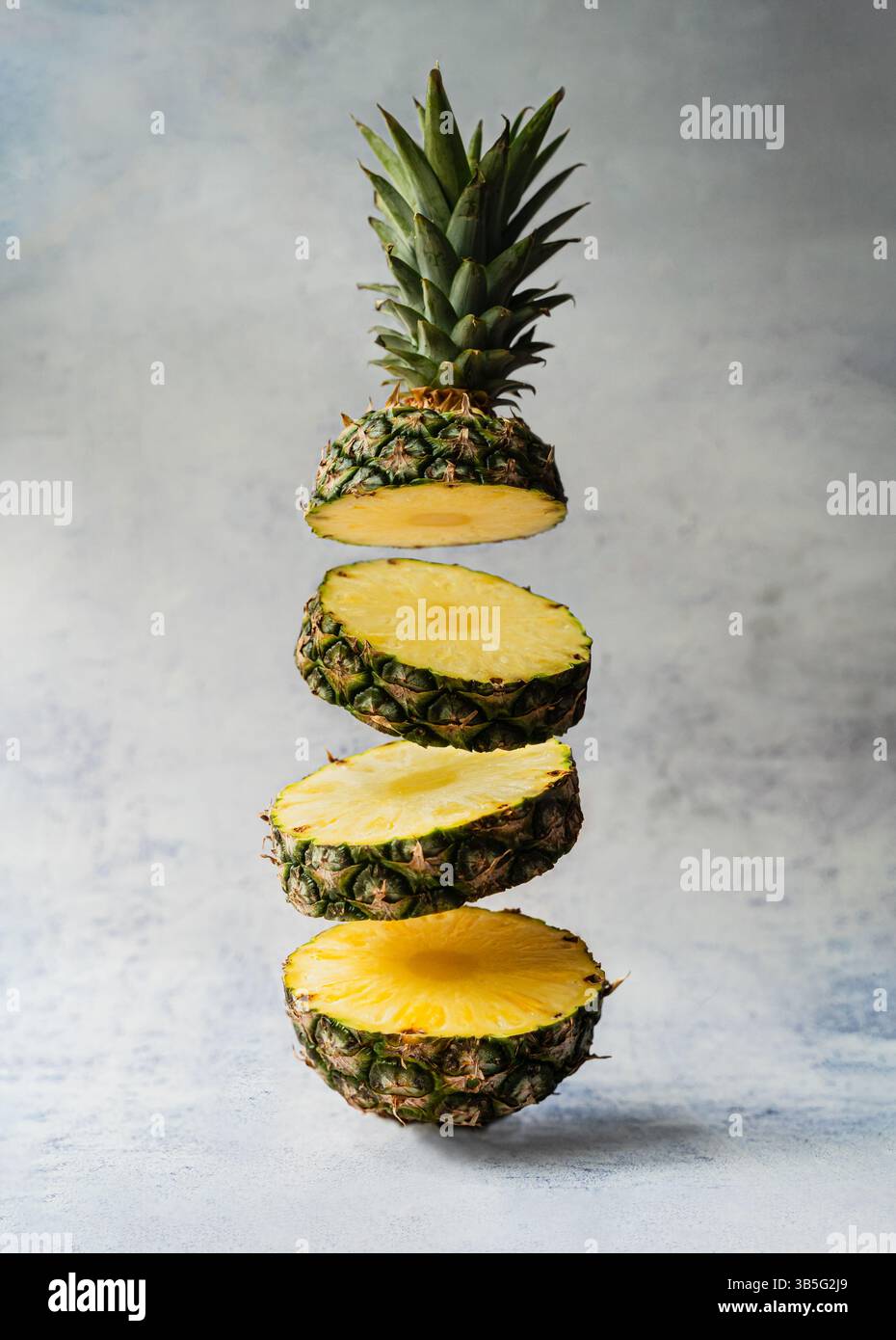 Fette fluttuanti di succoso ananas su sfondo chiaro. Foto Stock