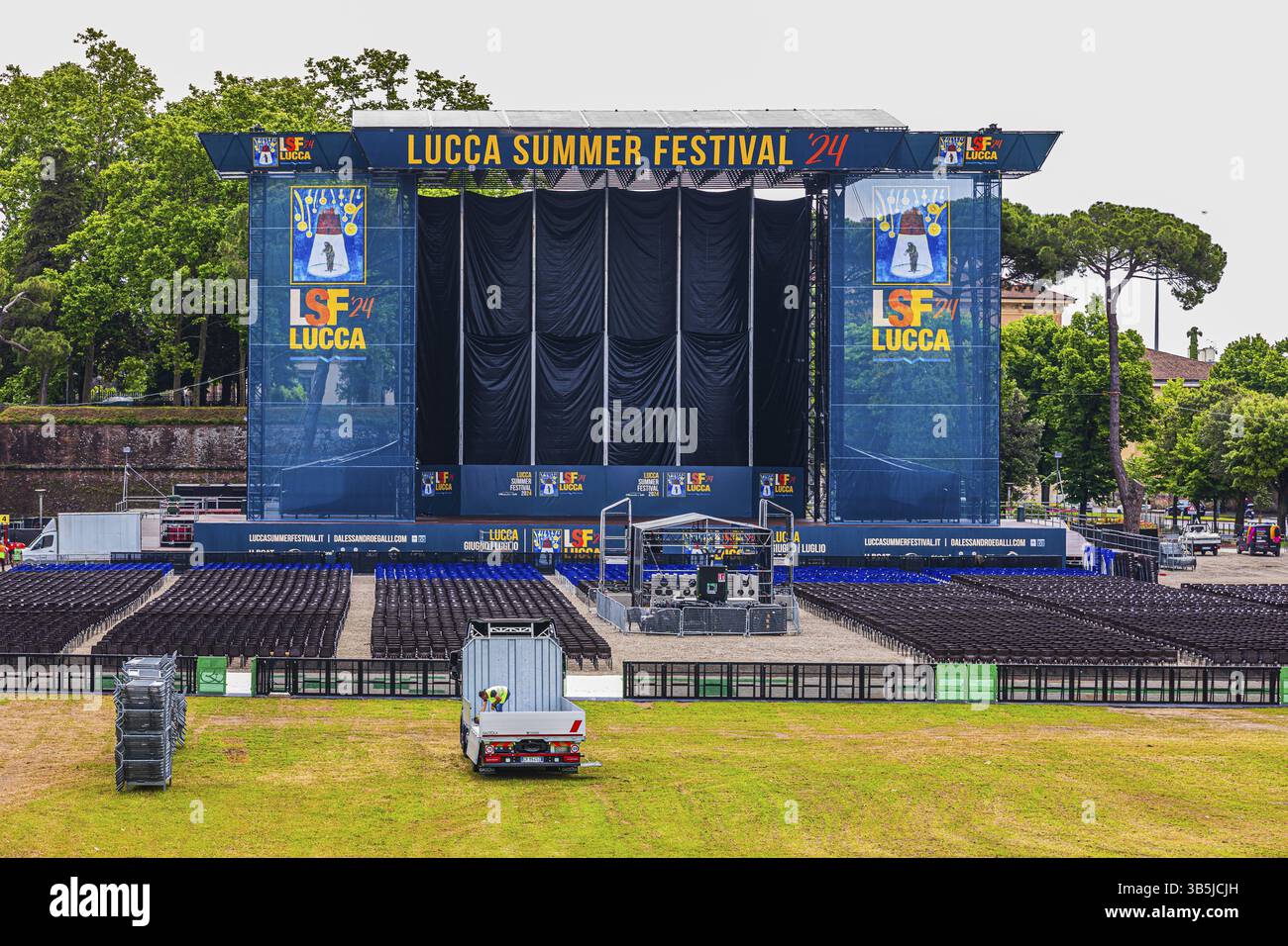 File blu e nere di sedie nell'area del pubblico, il grande palco sul retro, Festival estivo, Lucca, Toscana, Italia, Europa Foto Stock